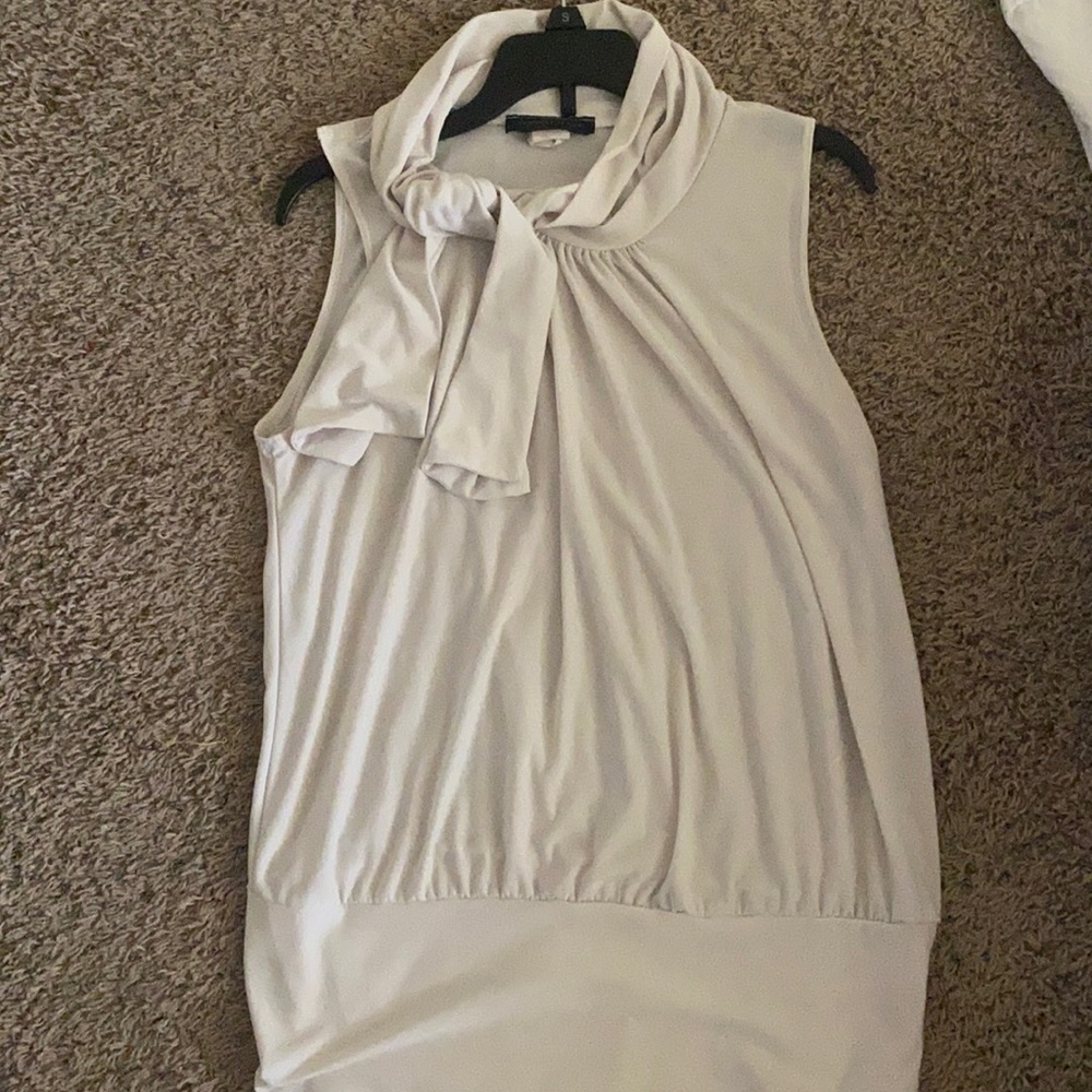 Sleeveless white blouse. High neck with adjustable tie on neckline